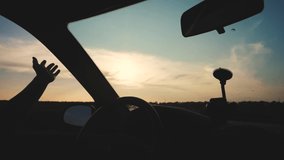 travel freedom concept. slow motion video. Drivers hand plays with the sun from a car window on a background of a beautiful sunset. long road sunset evening driver stuck his hand out of lifestyle a