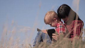 happy family concept Mother and son slow motion video. Mom girl and son Little boy with digital internet tablet work and play the final light lifestyle flare outdoors. life happy family care love