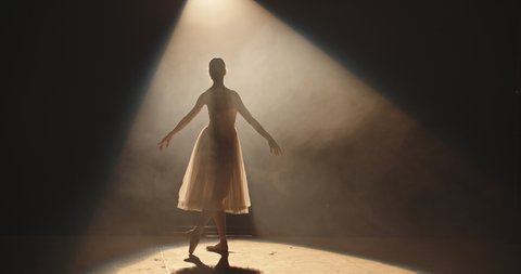 Female ballet dancer performing on theatre stage, dancing while spotted by bright light, isolated on black background - arts concept 4k footage