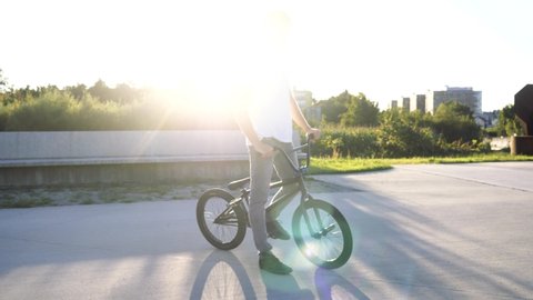 SLOW MOTION Young bmx biker fooling around with bmx bike in city park in sunny summer day
