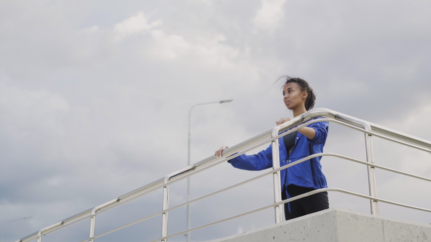 Afro-american runner woman in blue jacket finishing running