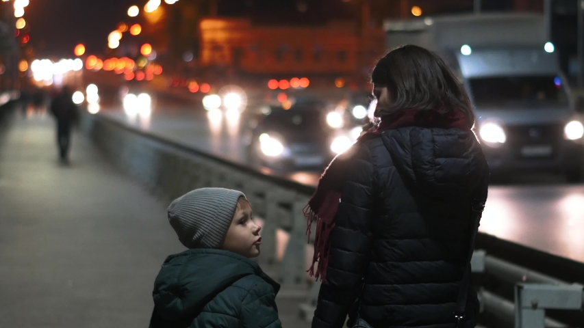 Mom and son walk around the night city
