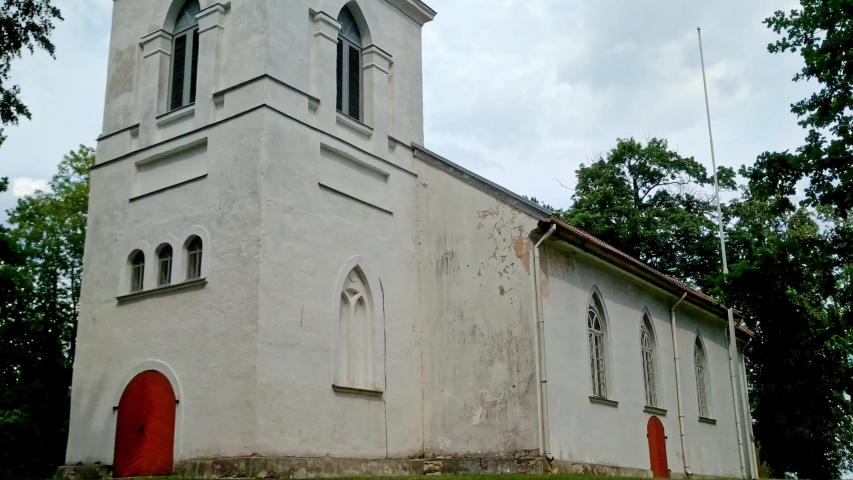 Looking up at the Evangelical Lutheran Church of Skrunda from the front, admiring the spire through the treetops