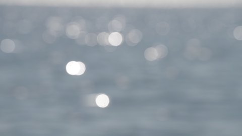 Blue and sparkling Bokeh light background in the sea. reflecting in the sunlight with a bokeh. Defocused shot of a water surface with a beautiful bokeh of sun glares which are reflected from the sea 