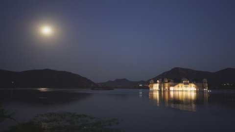 a night shot of jal mahal palace, lake man sagar and a full moon in jaipur, india