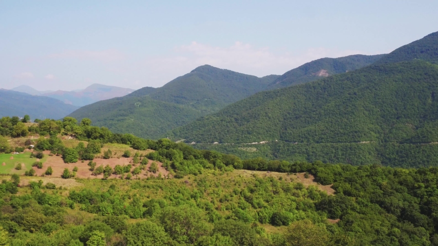 Emerald lake in Caucasian Mountains, forest hilly at summer sunny day - Aerial drone view