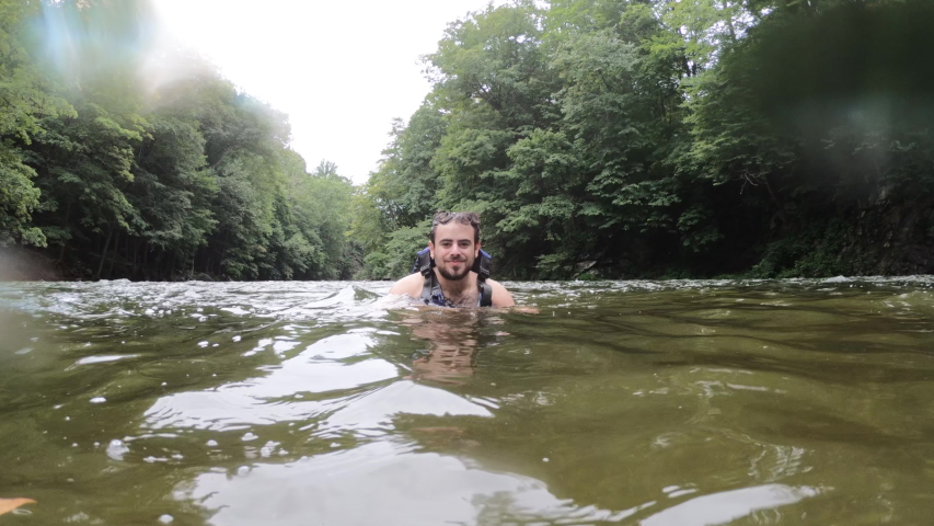 Man waving in the water and then dunking.  Slow motion video.
