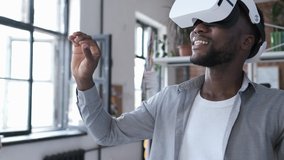 Handsome african american man wearing virtual reality headset. Augmented Reality. Man touch something using modern 3D vr glasses indoors. Student playing using VR glasses on a sunny day. Shot on 4K - Powered by Shutterstock - Get 15% off with code: PIKWIZARD15