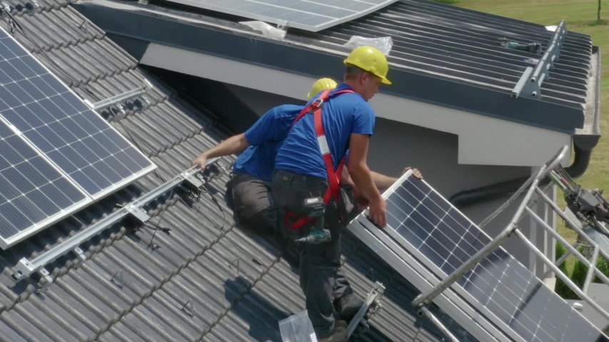Two workers laying down and installing PV (Photovoltaic) solar panels on the roof of a house,which converts solar energy into electric energy.Concept of professionalism,job,work. | Shutterstock HD Video #1038923135