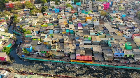 Aerial: Crowded houses in slum by modern residential buildings and sea - Mumbai, India