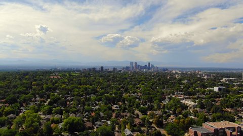 Aerial: Denver Skyline with Stunning Sky in Front of Rocky Mountains - Denver, Colorado