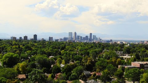 Aerial: Denver Skyline on Sunny Day Over Richly Forested Neighborhoods - Denver, Colorado