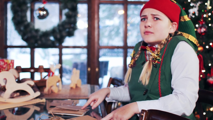 Elf girl sitting at the table with New Year