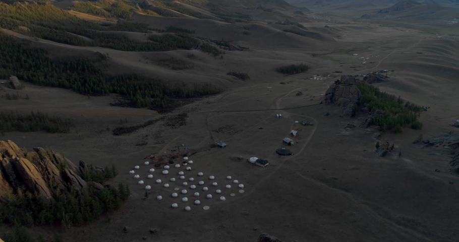 Drone reversing from traditional white houses on land with trees and rock formations - Ulaanbaatar, Mongolia