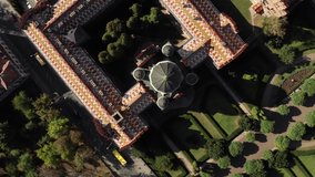 Old building of Chernivtsi University with few domes and a green garden with walkways in Ukraine. Sun is shining on them. Aerial video recording with zooming in and rotation.