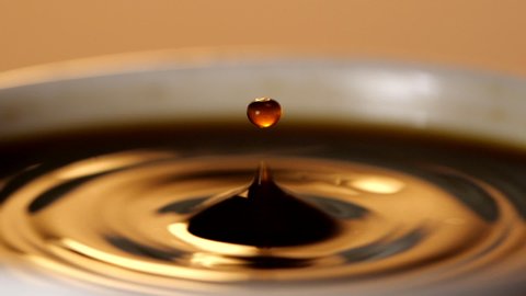 Black coffee drop into the filled Cup from the coffee machine in slow motion