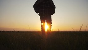 man tourist with backpack silhouette travel goes on an adventure. sunset time sunlight. slow motion video hiker walks with backpacks on green grass field lifestyle . adventure concept