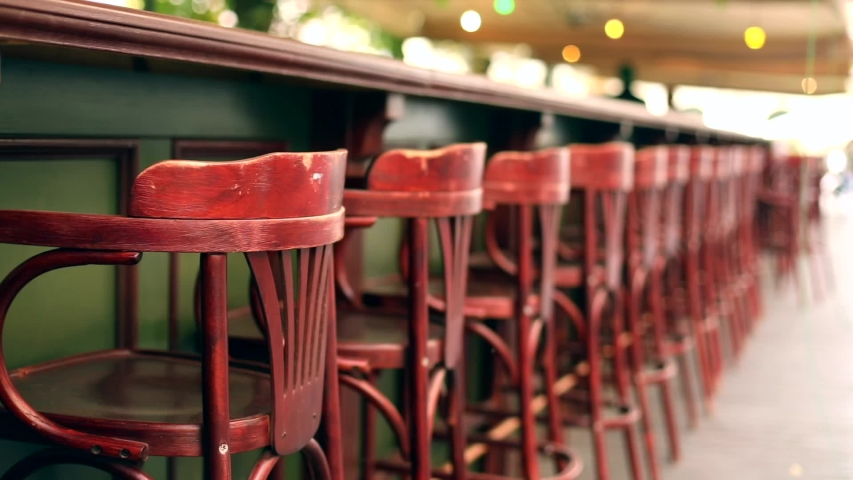 Slow mo view of empty red bar retro chairs wooden stool outdoor with sun light on background. Restaurant business, coffee shop cafe cafeteria service. Modern stylish interior, exterior.Nobody. Royalty-Free Stock Footage #1038946145