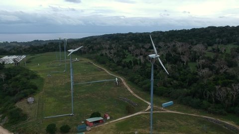 Aerial view of a wind farm situated on a mountain top near the coastline of a tropical island in the Pacific ocean region