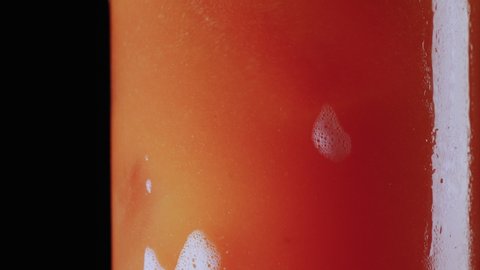 Macro shot of a bartender stirring in a bloody mary drink cocktail with a spoon in a glass filled with ice
