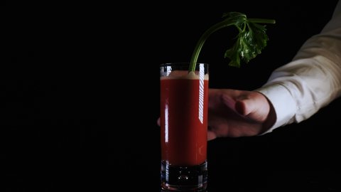 Bartender presents a fresh Bloody Mary drink Cocktail isolated on black background