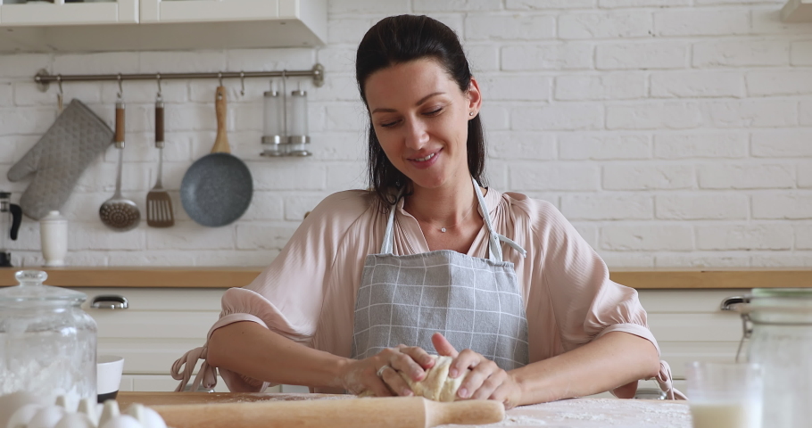 Happy young woman wear apron kneading dough for pizza with hands flour baking pastry at home, smiling lady housewife cooking in modern kitchen alone preparing pie cake or handmade cookies on table Royalty-Free Stock Footage #1038952430