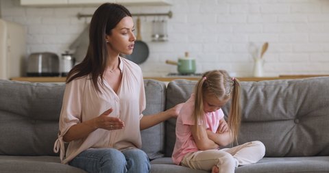 Angry young mother scolding shouting at stubborn fussy little kid daughter demand discipline lecturing disobedient difficult rebellious child ignoring not listening to annoyed mom sit on sofa at home