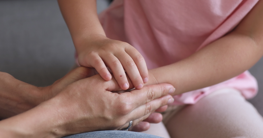 Adult woman mother and little cute child daughter holding hands as parent child love protection support concept, kid adoption, foster care, family trust connection and kindness, close up view | Shutterstock HD Video #1038952487