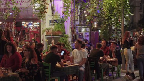Thessaloniki, Greece - October 12 2019: Hellenic nightlife video of people at outdoors tavern restaurants. Unidentified crowd eating & drinking at tavernas in the center at Ano Ladadika area.