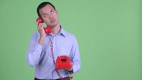 Young businessman giving telephone to stressed Asian businessman looking bored - Powered by Shutterstock - Get 15% off with code: PIKWIZARD15