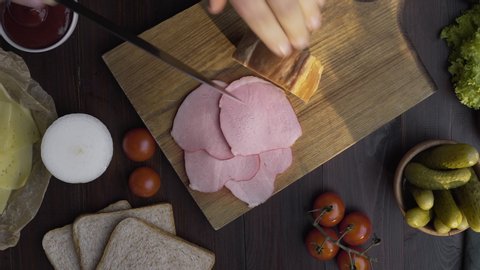 Tabletop video of tasty natural ham is sliced by sharp knife on the wooden board, jerky smoked meat, making of the sandwich with sliced ham, meat cooking, at the butcher shop, 4k UHD Prores HQ 422