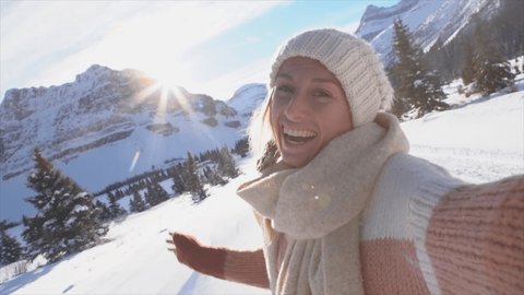 Young woman on a winter vacation takes a selfie surrounded by snowy landscape. Woman travelling in Canada during Christmas season takes a video selfie. Slow motion 