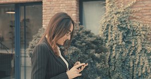 Attractive business woman with eye glasses smiling portrait. Young business people confident pretty. Female goes with smartphone in the city. Growing, success. 4K slow motion video