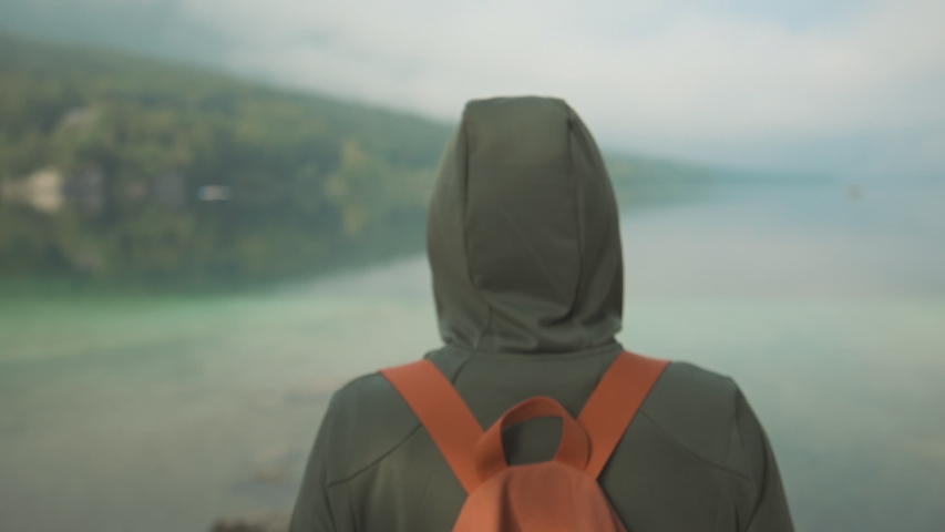 Rear view of female hiker enjoying the view of lake in misty summer morning, handheld footage