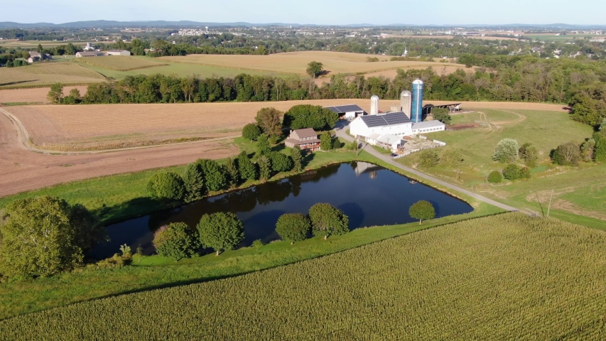 Aerial view of a dairy farm and buildings, pond in Lancaster County Pennsylvania, drone tracking parallax, pan left long shot