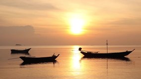 A beautiful golden tripod video of the sunsetting in Thailand with traditional Thai fishing boats in the foreground.