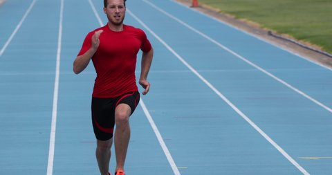 Sprinter man running sprint training on athletics track and field stadium fast at high speed. Male athlete runner in intense sprint exercise. Run sport concept. REAL TIME.