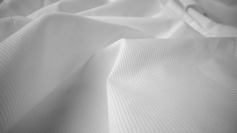 Shiny flowing cloth texture dolly shot in close up view macro shot. Wavy clean silk weave material. Textile abstract background. Bed sheet, curtain and clothing industry concept.
