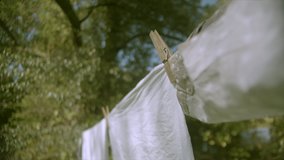 Clean white laundry sheets hang on line in fresh outside air and breeze, close up, shallow focus.