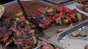 Video footage point of view shot a lot of grilled barbecue in warming pans. BBQ meat, bacon, chicken wing, sausage, meat, pork and vegetables. Street food