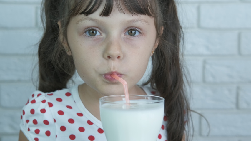 Milkshake for child. Joyful kid drink milkshake through a straw from the glass. | Shutterstock HD Video #1039029482