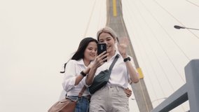 Happy Asian lesbian couples selfie video chat with friends enjoying traveling in Thailand. Beautiful young women having fun in vacation time. LGBT concept.