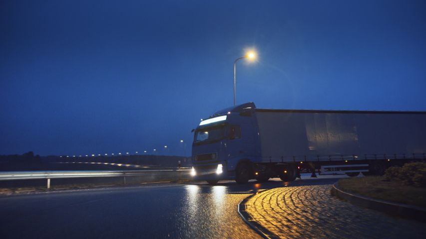 Blue Long Haul Semi-Truck with Cargo Trailer Full of Goods Travels At Night on the Freeway Road, Driving Across Continent Through Rain, Fog, Snow. Industrial Warehouses Area. Front Following Shot | Shutterstock HD Video #1039037258