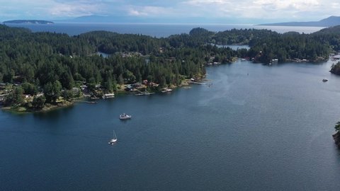 Aerial view over inlet, ocean and island with boat and mountains in beautiful British Columbia. Canada. 4K.