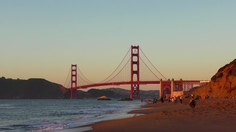 Unidentified people at Baker Beach in San Francisco, California at sunset, with the Golden Gate Bridge in the background, circa October 2018