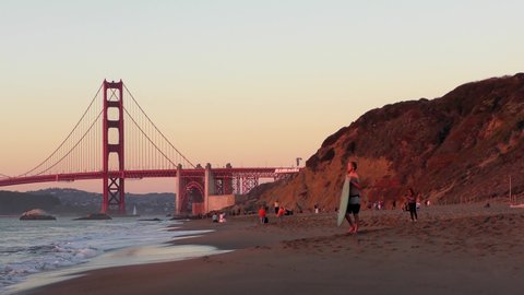 Unidentified people at Baker Beach in San Francisco, California at sunset, with the Golden Gate Bridge in the background, circa October 2018