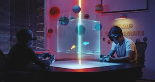 Medium long shot of teenagers playing holographic video game using joystick and vr augmented reality glasses