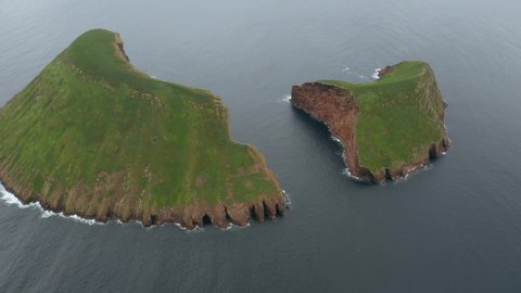Flying around a volcanic islets in the ocean. Aerial of Ilhus das Cabras, Terceira island, Azores