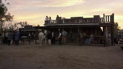 San Diego , CA / United States - 02 18 2019: Vintage period wild west reenactment scene in front of saloon building with authentic cowboy costume people walking in scene.