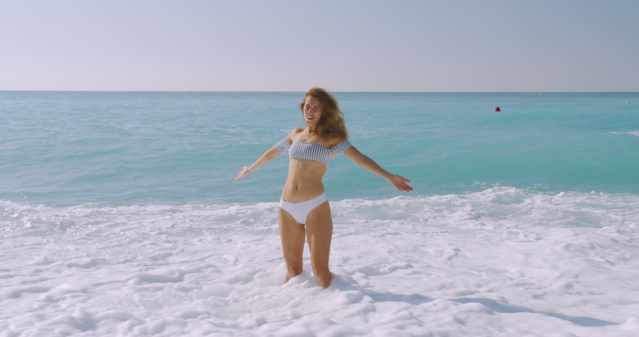 The woman carefree on the beatiful beach. The Girl relaxing, showing joy and happiness in slim body for weight loss diet concept on perfect white sand.